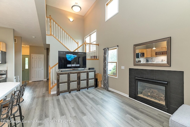 13689 Oneida Rd, Grand Ledge, MI 48837 - living room with light wood finished floors, stairway, healthy amount of natural light, a tile fireplace, and a high ceiling