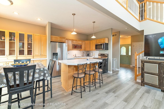 13689 Oneida Rd, Grand Ledge, MI 48837 - kitchen with appliances with stainless steel finishes, light wood-style floors, a center island, light countertops, and a breakfast bar