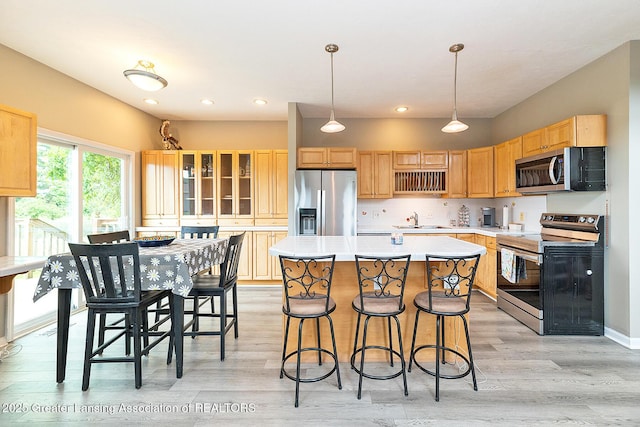 13689 Oneida Rd, Grand Ledge, MI 48837 - kitchen with appliances with stainless steel finishes, light countertops, light wood-style flooring, a center island, and recessed lighting