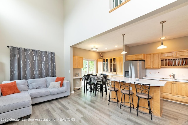 13689 Oneida Rd, Grand Ledge, MI 48837 - kitchen with stainless steel fridge, a breakfast bar area, light wood-style flooring, light countertops, and a high ceiling