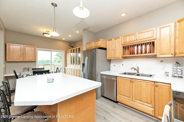13689 Oneida Rd, Grand Ledge, MI 48837 - kitchen featuring stainless steel appliances, tile counters, light wood-style flooring, decorative backsplash, and light brown cabinetry