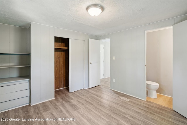 27508 F Dr S, Albion, MI 49224 - unfurnished bedroom featuring a textured ceiling, wood finished floors, a closet, and ensuite bath