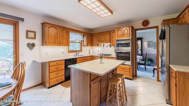 3888 Breckinridge Dr, Okemos, MI 48864 - kitchen featuring stainless steel appliances, a kitchen island, backsplash, and brown cabinetry