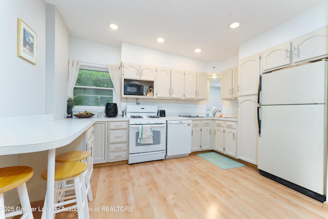 2162 Kent St, Okemos, MI 48864 - kitchen featuring white appliances, light countertops, light wood-style floors, a peninsula, and a breakfast bar area