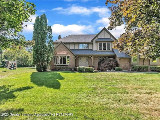 3619 W Arbutus Dr, Okemos, MI 48864 - tudor house with a chimney, a front yard, and brick siding