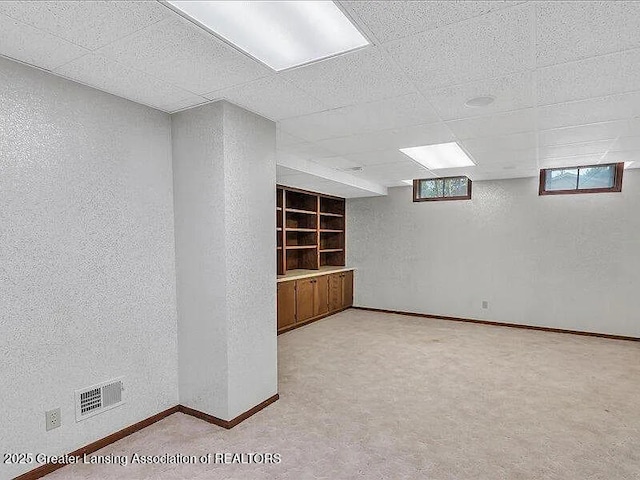 3619 W Arbutus Dr, Okemos, MI 48864 - below grade area with a paneled ceiling, light colored carpet, a textured wall, and built in shelves