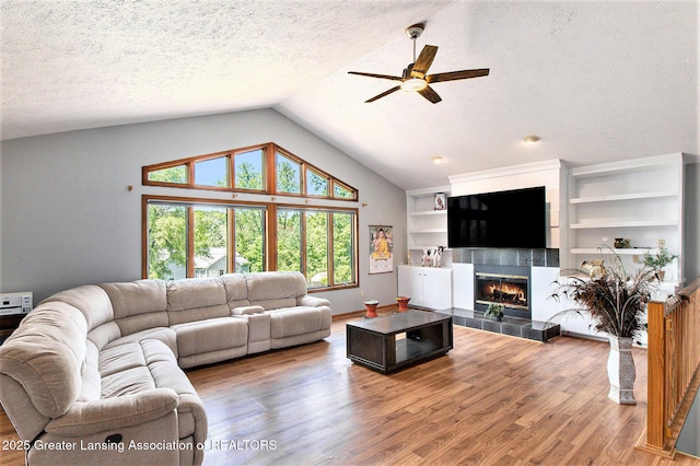 12829 Silver Ridge Dr, Grand Ledge, MI 48837 - living room featuring a ceiling fan, lofted ceiling, a fireplace, wood finished floors, and a textured ceiling
