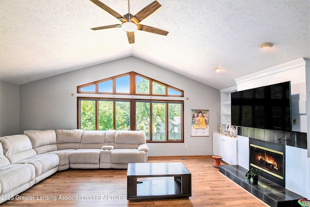 12829 Silver Ridge Dr, Grand Ledge, MI 48837 - living room featuring ceiling fan, a tile fireplace, wood finished floors, a textured ceiling, and lofted ceiling