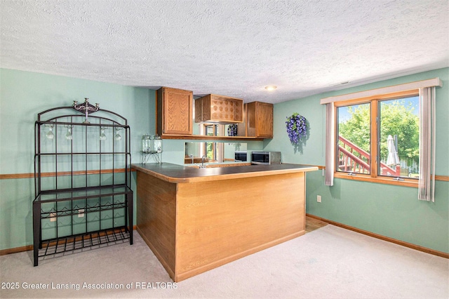 12829 Silver Ridge Dr, Grand Ledge, MI 48837 - kitchen with brown cabinetry, stainless steel microwave, a textured ceiling, a peninsula, and open shelves