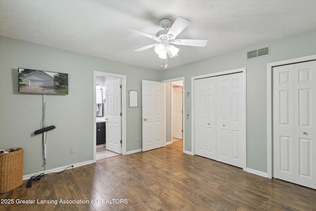 207 Queens Ct Unit 8, Grand Ledge, MI 48837 - unfurnished bedroom with wood finished floors, multiple closets, connected bathroom, and a ceiling fan