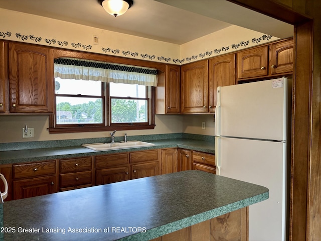 234 W Grand Ledge Hwy Unit R1, Mulliken, MI 48861 - kitchen featuring freestanding refrigerator, dark countertops, and brown cabinets