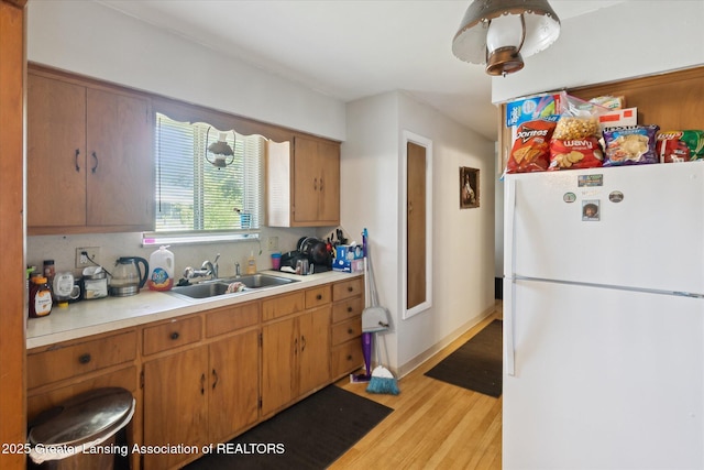 1117-1119 Blake Ave, Lansing, MI 48912 - kitchen with freestanding refrigerator, light wood-style flooring, light countertops, and brown cabinets