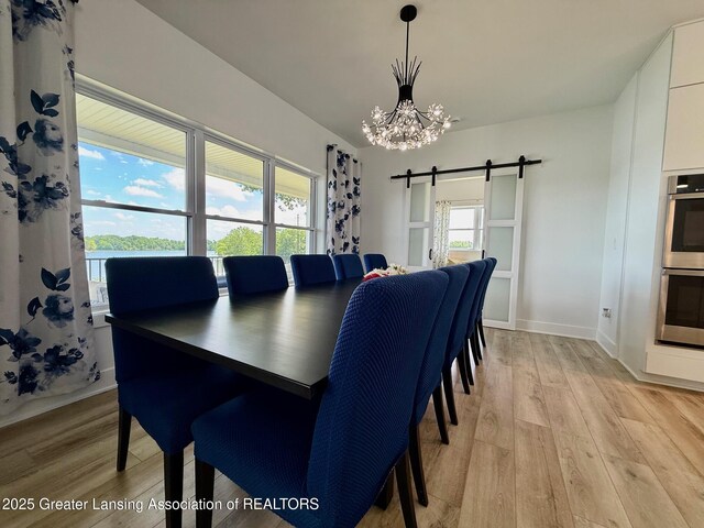10993 Lakeside Dr, Perrinton, MI 48871 - dining space featuring a chandelier, a barn door, and light wood finished floors