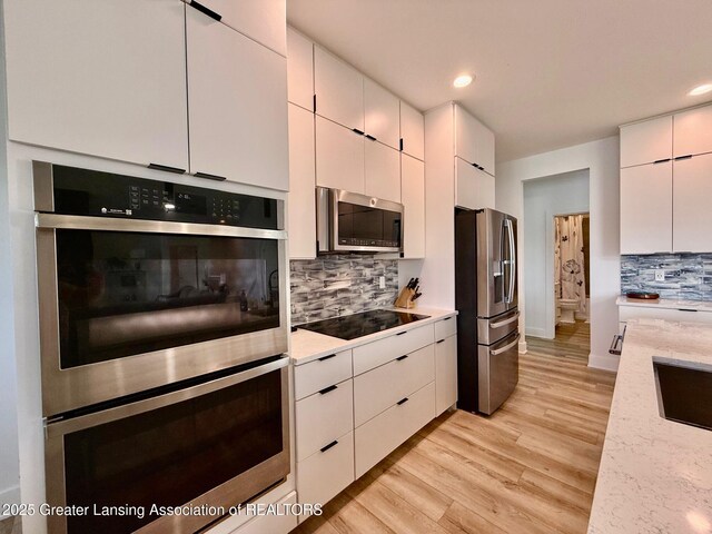 10993 Lakeside Dr, Perrinton, MI 48871 - kitchen featuring stainless steel appliances, tasteful backsplash, white cabinetry, light wood-type flooring, and recessed lighting