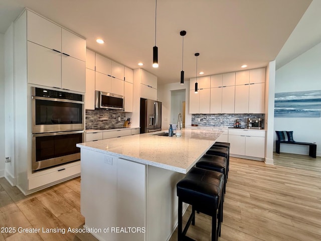 10993 Lakeside Dr, Perrinton, MI 48871 - kitchen featuring appliances with stainless steel finishes, modern cabinets, backsplash, light wood-style flooring, and recessed lighting