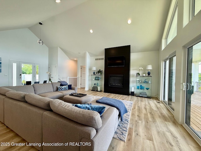 10993 Lakeside Dr, Perrinton, MI 48871 - living area with high vaulted ceiling, a fireplace, light wood-type flooring, and french doors
