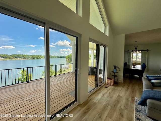 10993 Lakeside Dr, Perrinton, MI 48871 - doorway to outside featuring a water view, a chandelier, high vaulted ceiling, and light wood-type flooring