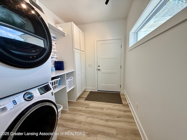 10993 Lakeside Dr, Perrinton, MI 48871 - laundry room featuring stacked washer and clothes dryer, cabinet space, and light wood-style floors