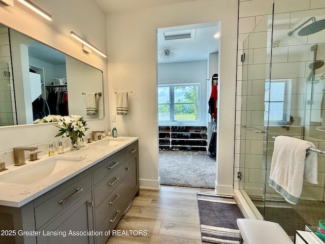 10993 Lakeside Dr, Perrinton, MI 48871 - bathroom featuring wood finished floors, double vanity, a stall shower, and a spacious closet