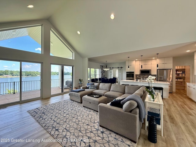 10993 Lakeside Dr, Perrinton, MI 48871 - living area with high vaulted ceiling, a water view, light wood-style floors, recessed lighting, and a chandelier