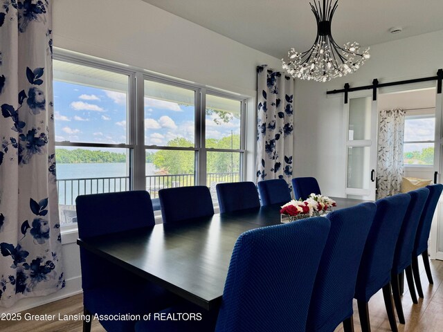 10993 Lakeside Dr, Perrinton, MI 48871 - dining area with a chandelier, wood finished floors, a barn door, and a water view