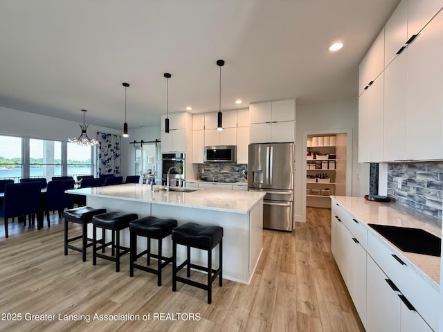 10993 Lakeside Dr, Perrinton, MI 48871 - kitchen with stainless steel appliances, modern cabinets, a kitchen bar, decorative backsplash, and light wood finished floors