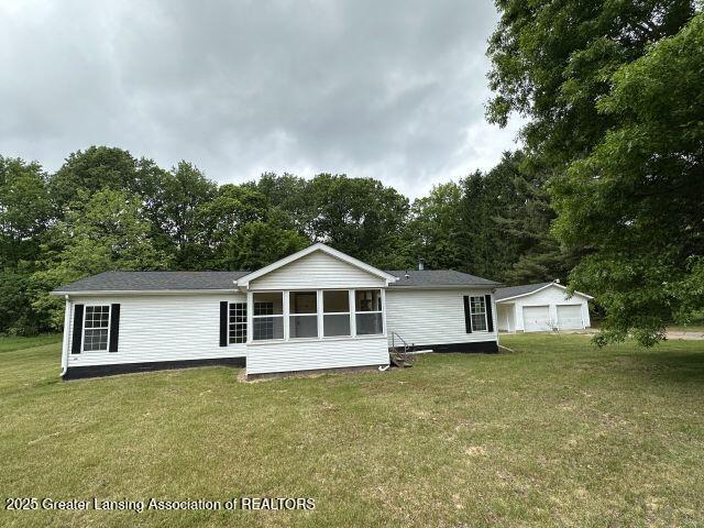 8241 Barson Rd, Rives Junction, MI 49277 - rear view of property featuring a detached garage, a yard, a sunroom, and view of wooded area
