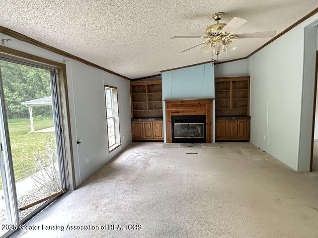 8241 Barson Rd, Rives Junction, MI 49277 - unfurnished living room featuring crown molding, ceiling fan, a fireplace with flush hearth, light carpet, and a textured ceiling
