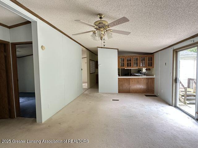 8241 Barson Rd, Rives Junction, MI 49277 - unfurnished living room with a textured ceiling, crown molding, light carpet, and ceiling fan
