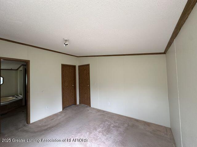 8241 Barson Rd, Rives Junction, MI 49277 - unfurnished bedroom featuring carpet, crown molding, and a textured ceiling