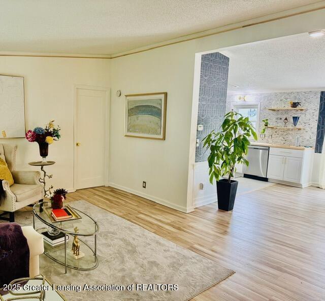 4340 Balmoral Dr, Lansing, MI 48911 - living room featuring light wood-style flooring, a textured ceiling, and ornamental molding