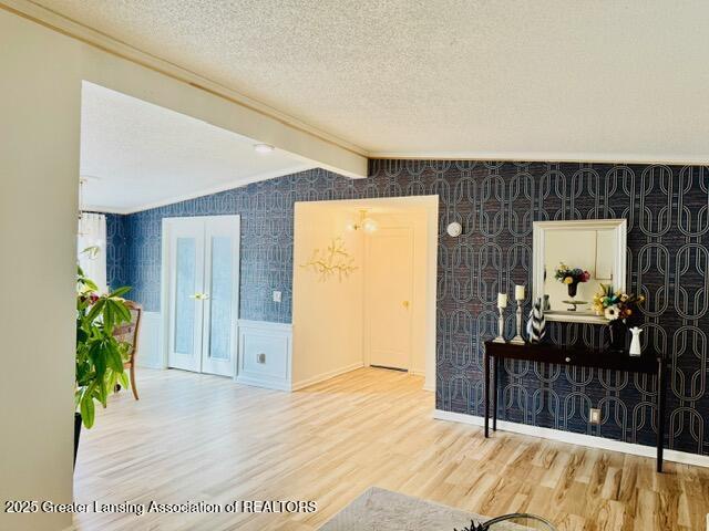 4340 Balmoral Dr, Lansing, MI 48911 - unfurnished living room with wood finished floors, a textured ceiling, wallpapered walls, and ornamental molding