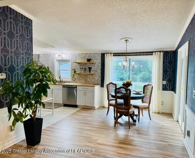 4340 Balmoral Dr, Lansing, MI 48911 - dining space featuring a textured ceiling, light wood finished floors, a chandelier, and ornamental molding