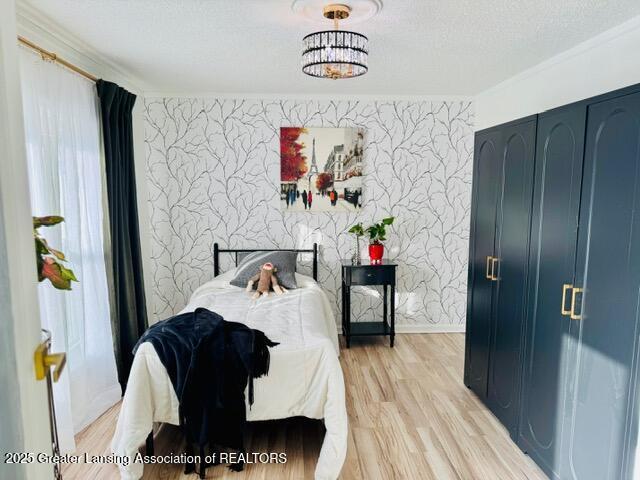 4340 Balmoral Dr, Lansing, MI 48911 - bedroom with light wood-type flooring, ornamental molding, and an accent wall