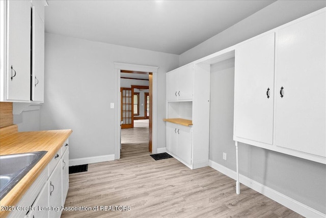 916 Wildwood Ave, Jackson, MI 49202 - kitchen with white cabinetry, light wood-type flooring, and light countertops