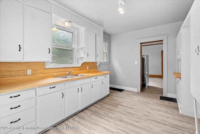 916 Wildwood Ave, Jackson, MI 49202 - kitchen with light countertops, white cabinets, tasteful backsplash, and light wood-type flooring