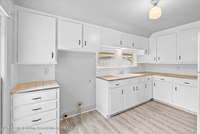 916 Wildwood Ave, Jackson, MI 49202 - kitchen with light wood finished floors, light countertops, tasteful backsplash, white cabinets, and vaulted ceiling