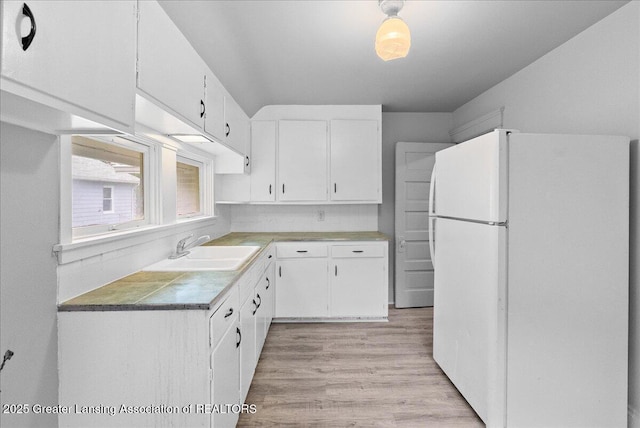 916 Wildwood Ave, Jackson, MI 49202 - kitchen with freestanding refrigerator, light wood-type flooring, and white cabinets