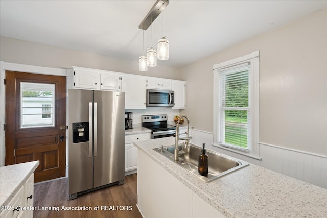409 E Higham St, Saint Johns, MI 48879 - kitchen featuring stainless steel appliances, dark wood-style floors, healthy amount of natural light, white cabinetry, and a wainscoted wall