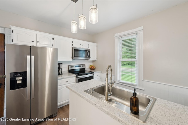 409 E Higham St, Saint Johns, MI 48879 - kitchen with appliances with stainless steel finishes, white cabinetry, a wainscoted wall, hanging light fixtures, and dark wood finished floors