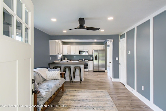 304 W Gibbs St, Saint Johns, MI 48879 - kitchen with stainless steel appliances, white cabinetry, a ceiling fan, light wood-type flooring, and dark countertops