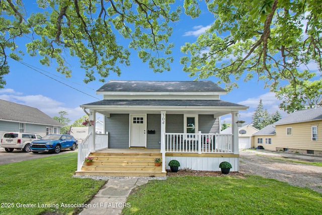 304 W Gibbs St, Saint Johns, MI 48879 - view of front of property featuring covered porch, a front yard, roof with shingles, and driveway