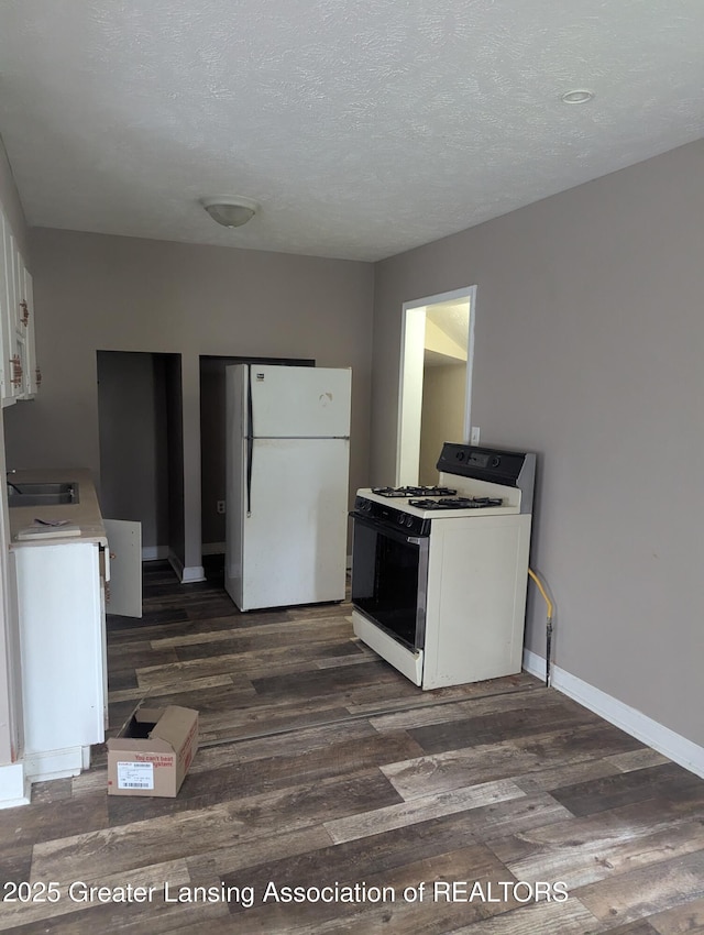 527 S Charles St, Lansing, MI 48912 - kitchen featuring white appliances, dark wood-style floors, white cabinetry, a textured ceiling, and light countertops