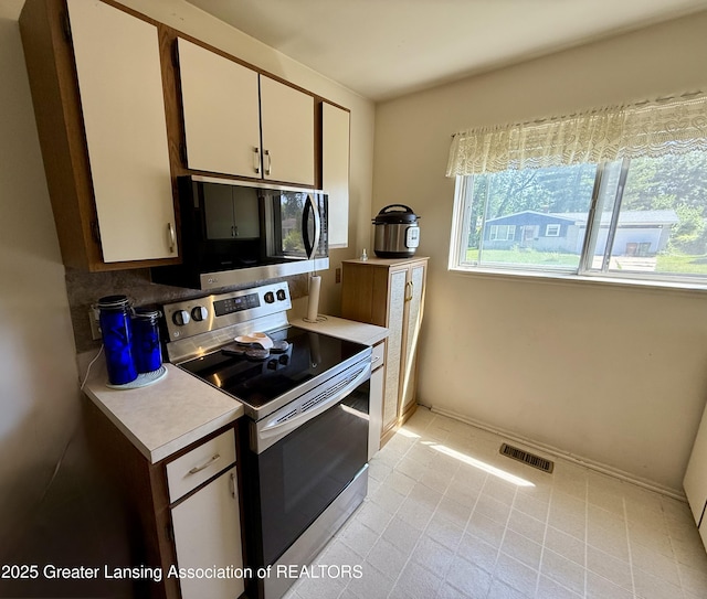 3618 Alpine Dr, Lansing, MI 48911 - kitchen featuring stainless steel appliances, white cabinets, light countertops, and light tile patterned flooring