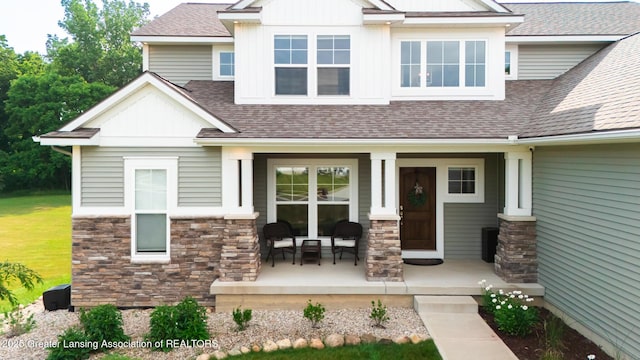 9655 Tobermory Dr, Haslett, MI 48840 - view of front of home featuring covered porch, a shingled roof, and stone siding
