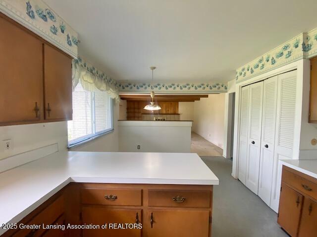 12906 Bilmar Ln, Grand Blanc, MI 48439 - kitchen with a peninsula, light countertops, hanging light fixtures, and brown cabinets