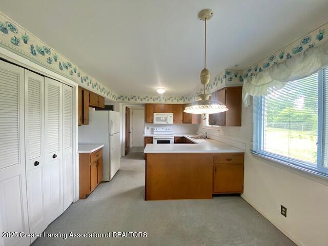12906 Bilmar Ln, Grand Blanc, MI 48439 - kitchen with white appliances, light countertops, a peninsula, and brown cabinets