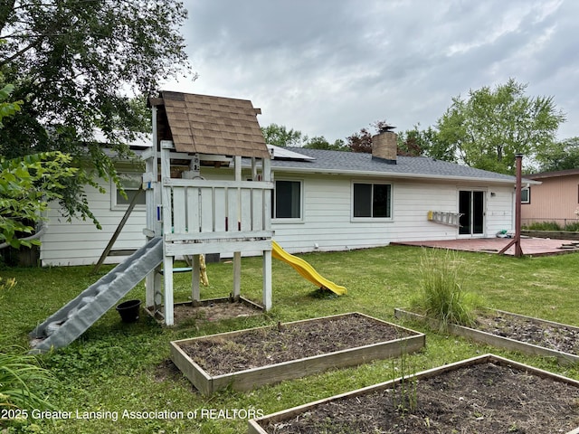 1023 E Colonial Park Dr, Grand Ledge, MI 48837 - rear view of property with a garden, a playground, a yard, a chimney, and roof with shingles