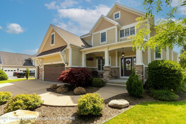 6075 Sacramento Way E, Lansing, MI 48823 - craftsman-style house with covered porch, stone siding, concrete driveway, and a shingled roof