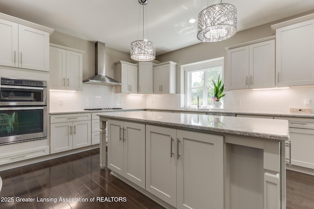 6075 Sacramento Way E, Lansing, MI 48823 - kitchen with wall chimney range hood, double oven, gas stovetop, backsplash, and a center island
